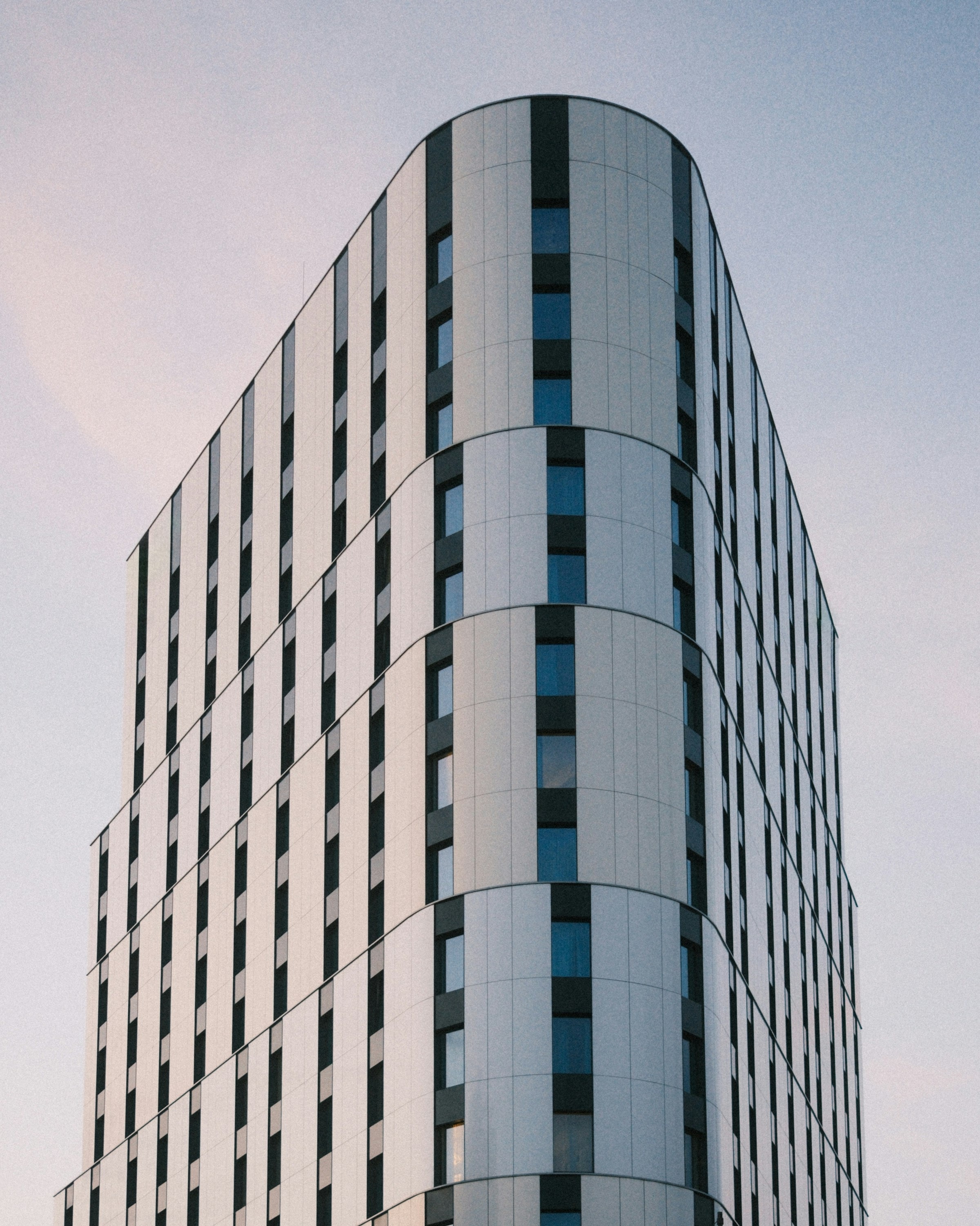 Curved-corner commercial tower against a dusk sky